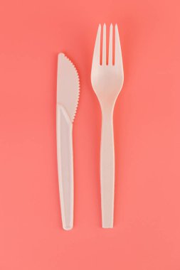 Üst çekim pembe arka plan çift plastik beyaz bıçaklar ve çatallı sofra takımı ekolojik teknoloji Gezegen piknik seti için yeniden kullanılabilir