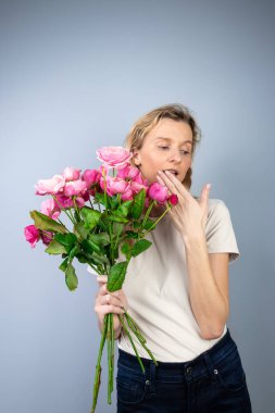 Açık gri arkaplan büyük bir buket pembe güllü bayanla genç bir kız tatili. 8 Mart 'ta ilk buluşmada yüzünde duygular belirdi. Şaşıran kız ağzını eliyle kapattı. 