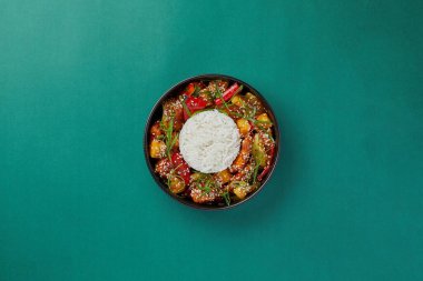 Mavi arka plan siyah salata tabağında Çin pilavı ve ananaslı ekşi soslu tavuk sağlıklı yemek.