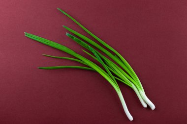 Zengin bir bordo arka planda sergilenen canlı yeşil soğanlar, çeşitli mutfak yemeklerinde taze tazeliklerini ve çok yönlülülüklerini sergiliyorlar..