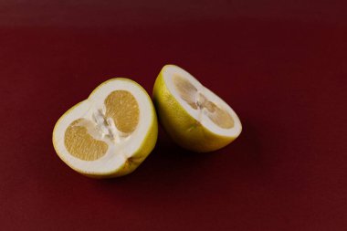 Işıl ışıl sarı bir meyvenin iki yarısı derin bir kestane rengi arka planda, sulu iç görünüşünü ve davetkar görünümünü gözler önüne serer, aşçılık yaratıcılığı ve sağlıklı beslenme için ideal..