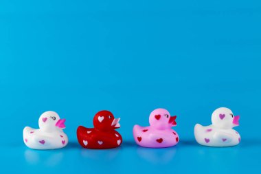 Her biri kalp desenleriyle süslenmiş dört renkli lastik ördekten oluşan hoş bir düzenleme, canlı mavi bir zemin üzerine kurulmuş, çocuklar için mükemmel olan eğlenceli ve kaprisli bir titreşim yakalıyor..