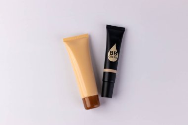Cilt geliştirme için tasarlanmış çeşitli gölgelerin sergilendiği iki farklı BB kremi tüpü günlük güzellik rutinlerinde ulaşılabilirliği ve yaratıcılığı göstermektedir..
