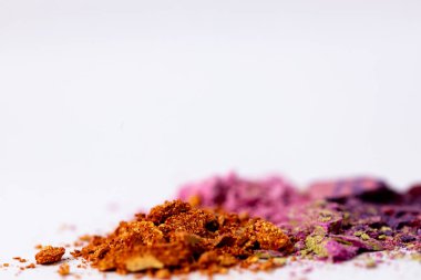 Turuncu, mor ve yeşil renklerde, yaratıcı zanaat, makyaj ya da sanat projeleri için ideal, görsel cazibeyi gösteren ince renkli tozların sanatsal bir gösterimi..