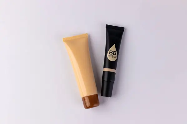 Cilt geliştirme için tasarlanmış çeşitli gölgelerin sergilendiği iki farklı BB kremi tüpü günlük güzellik rutinlerinde ulaşılabilirliği ve yaratıcılığı göstermektedir..