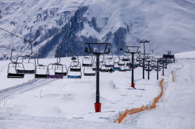 Bu görüntü, görkemli dağlar ve sakin bir atmosferle çevrili el değmemiş kar üzerinde süzülen boş kayak asansörleriyle pitoresk bir kış görüntüsü yakalıyor. Kış sporu severler için mükemmel..