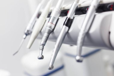 Görüntü, diş sağlığı ve diş sağlığı teknolojisindeki ilerlemenin hasta tedavisi için önemini vurgulayan, çağdaş bir diş sandalyesine yerleştirilmiş bir dizi diş aletini gösteriyor..