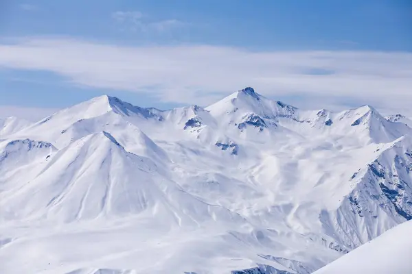 Bu resim, parlak mavi gökyüzünün altında muhteşem karla kaplı dağları sergiliyor. Soğuk ve güzel kışları somutlaştırıyor. Huzurlu bir manzara keşfi ve doğada macerayı davet ediyor..