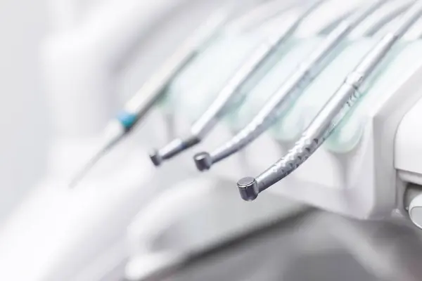 Bu resimde, modern bir diş muayenehanesinde profesyoneller tarafından kullanılan çeşitli diş aletleri gösteriliyor, oral sağlık ve hijyen üzerine odaklanan prosedürler için gerekli aletler vurgulanıyor.