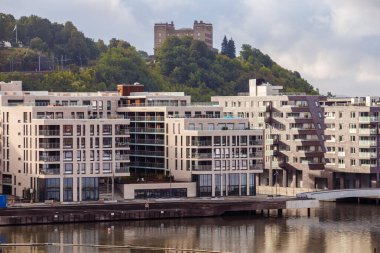 Bu resimde, sakin bir sahil şeridi boyunca yer alan ve tarihi öneme sahip çarpıcı bir zemin oluşturan güzel bir dizi modern apartman var..
