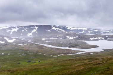 Bu nefes kesici manzara Norveç dağlarının güzelliğini gözler önüne seriyor. Huzurlu sular, yuvarlanan tepeler ve kar örtüsüyle süslenmiş dağlar sakin bir atmosfer yaratıyor..