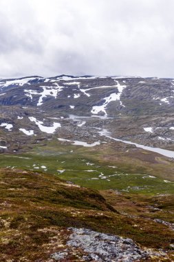 Bu nefes kesici görüntü, vadide yerleşmiş sakin gölü olan görkemli kar örtülü dağları sergiliyor. Kuzeyli doğal manzaranın huzur dolu güzelliğini yansıtıyor..