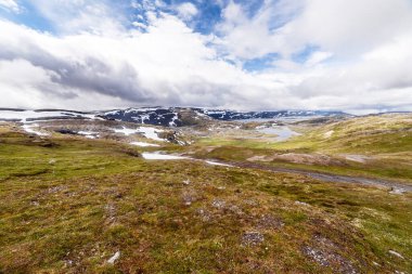 Karla kaplı tepelerin çarpıcı kontrastını gösteren bu nefes kesici alp manzarasını keşfedin, yeşil araziler, ve suyun sakin gövdesi güzelliği ve ihtişamı yansıtır..