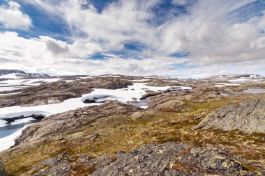 Uçsuz bucaksız kayalıklar kar ve durgun su parçalarıyla kaplı. Büyüleyici mavi bir gökyüzü altında beyaz bulutlarla bezenmiş, çarpıcı bir doğa manzarası yaratıyor..