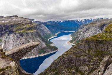 Bu çarpıcı görüntü, yüksek uçurumlar ve engebeli dağlar arasında yuva yapmış sakin bir Norveç fiyordunu gözler önüne seriyor, çarpıcı bir gökyüzü nefes kesici manzara manzarasına derinlik katıyor..