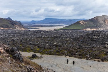 İzlanda 'nın nefes kesici manzarası engebeli dağların, geniş lav tarlalarının ve bulutlu bir günde eşsiz manzarayı keşfeden meraklı yürüyüşçülerin dramatik bir karışımını sergiliyor..