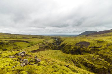 Bereketli, yeşil vadilerin ve İzlanda 'nın derin, dramatik kanyonlarının bulutlu bir gökyüzü tarafından çerçevelenmiş nefes kesici manzarasını keşfedin ve karanın güzelliğine çarpıcı bir bakış sunun..