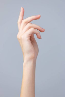 Güzel konumlanmış bir el ince gri bir arka plana karşı sergilenir, sanatsal ışık dolu bir ortamda parmaklarımızın ve bileğimizin zarafetini ve zarafetini vurgular..
