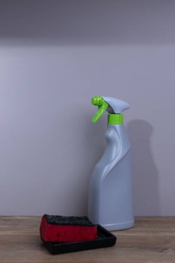 Bu resim, bir süngerin yanında parlak bir sprey şişesi sunuyor, her ikisi de ev ortamında etkili temizlik için gerekli aletler, pratik tasarım ve işlevsellik sunuyor..