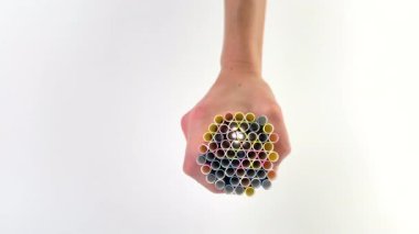 Beyaz arka planda, bir kadın eli kokteyller için bir avuç renkli pipet, soğuk ve sıcak içecekler için çizgili pipet, yaz havası, bar ekipmanları, pipetlerin içinden ışık