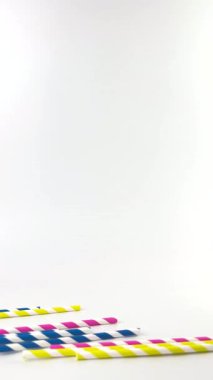 dikey renkli kokteyl pipetleri beyaz arka planda yuvarlanıyor. Soğuk ve sıcak içecekler için çizgili pipetler. Yaz havası. Bar ekipmanları. Sarı, pembe ve mavi. Beyaz çizgiler. Çapraz çizgiler.