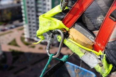 Bu görüntü, yüksek irtifa inşaatında kullanılan güvenlik kayışlarının ve ekipmanların yakın plan çekimini ve yüksek binalardaki riskli görevler sırasında işçi korumasını sağlayan renkli kayışları vurguluyor.