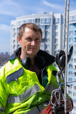 Yetenekli bir cam temizleyicisi, yüksek görünürlüklü giysiler içinde ve güvenlik teçhizatı ile donatılmış bir gökdelende görev yaparken yakalanır..