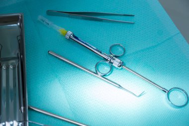 Mavi cerrahi perdelere yerleştirilmiş çeşitli cerrahi aletlerin yakın plan görüntüsü tıbbi operasyonlarda sterilizasyon ve organizasyonun önemini gösteriyor..