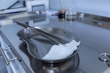 Cerrahi aletler ve steril gazlı bez içeren paslanmaz çelik tepsinin yakın plan görüntüsü, hasta güvenliği ve başarılı sonuçlar için klinik ortamlarda kullanılan temel ekipmanları vurguluyor.