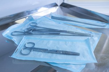 Görüntü, steril mavi ambalajlara titizlikle paketlenmiş çeşitli cerrahi gereçleri sergiliyor. Sağlık hizmetleri ortamında hijyen ve tıbbi prosedürlere hazır olmanın altını çiziyor..