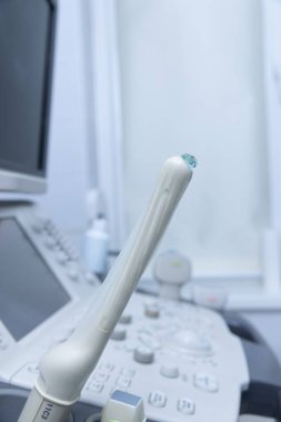 Gelişmiş bir ultrason makinesinin tepesinde ultrasonografi sondasını gösteren yakın plan bir görüntü klinik bir kurulum içinde tıbbi teşhislerdeki teknolojik gelişmeleri yansıtıyor..