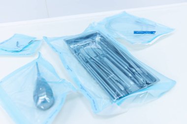 Görüntü, titizlikle paketlenmiş ve cerrahi veya klinik prosedürlerde kullanılmak üzere hazırlanmış çeşitli steril tıbbi araç ve gereç ve gereçleri sergiliyor..