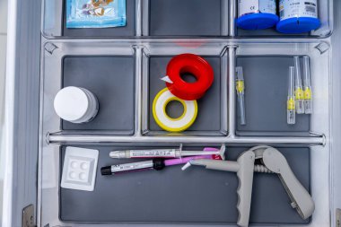Bu resim, tipik bir sağlık hizmetini veya laboratuvar kurulumunu gösteren, temel tıbbi gereçlerin, renk kodlu bantların, şırıngaların ve konteynırların düzenli bir düzenini yakalar..