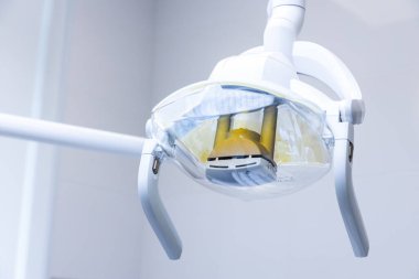 Bu resim, diş işlemleri için parlak ve odaklı aydınlatma, tedavi sırasında hastaların rahatlığı ve bakımını artırmak amacıyla tasarlanmış son model bir diş lambası sergiliyor..