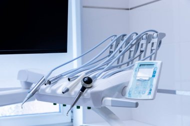 Görüntü, profesyonel bir klinik ortamında sergilenen ve hijyen ve ileri diş bakımı teknolojisini ön plana çıkaran son teknoloji diş aletleri ve ekipmanlara sahip..