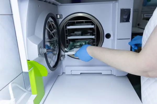 Bu görüntüde modern bir otoklavi sterilizatörü kullanan bir sağlık uzmanının tıbbi işlemlerde güvenlik için tıbbi araçların etkili bir şekilde sterilize edilmesini sağladığı görülüyor..