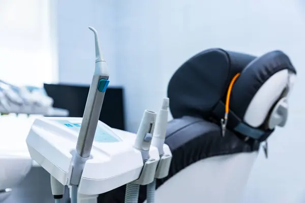 Çağdaş bir diş kliniğinde dişçi aletleri ve hasta sandalyesinin yakın plan görüntüsü, sakinleştirici renk şeması ile prosedürlere hazır iyi donanımlı bir alanı vurguluyor.