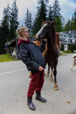 Neşeli bir kadın, çevresi ağaçlarla çevrili ve kırsal bir zemin ile çevrili pitoresk bir çevrede dost atlarla meşgul olur. Doğada insanlar ve hayvanlar arasında güzel bir bağ olduğunu gösterir..