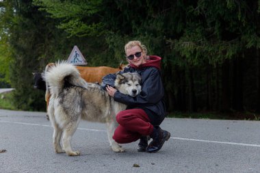 Bu huzurlu sahnede, neşeli bir birey ineklerle çevrili tüylü bir kabuğun yanında diz çöker, insanlar ve hayvanlar arasındaki bağı resmedilmeye değer bir doğa ortamında sergiler..