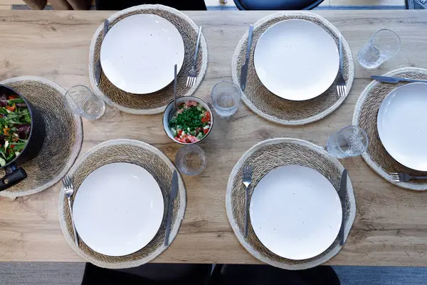 Lezzetli salata ve içeceklerle çevrili, beyaz tabaklı güzel bir yemek masası yemek için sıcak ve davetkar bir ortam yaratıyor..