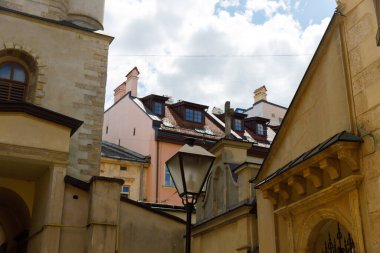 Karmaşık detayları ve modern çatıları olan, sokak lambası ve güzel bulutlu gökyüzü ile aydınlatılmış, tarihi binaların yer aldığı pitoresk bir sahne.