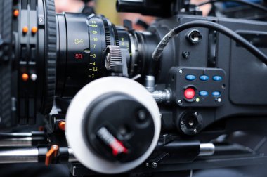 Resim, profesyonel film yapımında kullanılan anahtar bileşenleri ve yüksek kaliteli çıktılar için video kaydını vurgulayarak, bir kamera merceği ve kontrol panelinin ayrıntılı bir görünümünü gösteriyor..