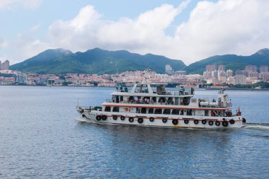 Görüntü, dingin sularda yüzen fevkalade bir turist teknesi yakalıyor. Dağlardan oluşan çarpıcı bir zemin ve canlı kentsel gelişim, keşif ve rahatlama için mükemmel..