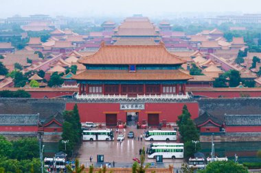 Görüntü Çin İmparatorluğu geçmişinin simgesel bir sembolü olan görkemli Yasak Şehir 'i yakalıyor, doğa ile çevrili, geleneksel çatıları ve tarihi önemi vurguluyor..