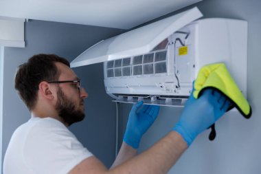 Yetenekli bir teknisyen, işlevselliğini ve hava kalitesini korumak için bir klimayı titizlikle temizliyor. Bu da havalandırma sistemlerinde düzenli bakımın önemini gösteriyor..