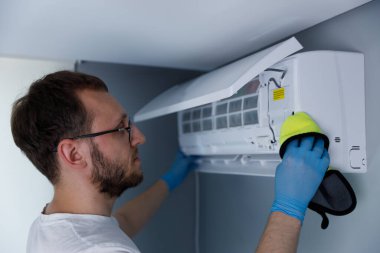 Görüntü, bir teknisyenin, daha iyi ev konforu ve sağlıklı yaşam ortamları için bakım ve hava dolaşımını geliştirmeye odaklanarak bir havalandırma ünitesini dikkatlice temizlediğini gösteriyor..