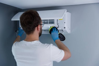 Yetenekli bir teknisyen, verimli bir işleyişi sağlamak ve gösterişli modern bir odada minimalist tasarımı olan hava kalitesini artırmak için bir havalandırma ünitesini özenle temizliyor..