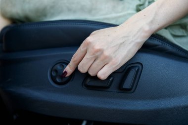 Otomobil koltuğunun ayarlama düğmesine basan bir elin yakın plan görüntüsü, araçlardaki rahatlığı artırmak için tasarlanmış ergonomik kontrol özelliklerini vurguluyor.