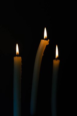 Görüntü, koyu bir arkaplanda ayakta duran üç mum içeriyor. Titrek alevleri, barışçıl yansımalar için ideal bir sıcaklık ve sakinlik ortamı yaratıyor..