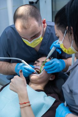 Klinik ortamda hastaya rahatlık ve bakım sağlarken diş aletlerini kullanarak oral sağlık prosedürü uygulayan dişçi randevusu.